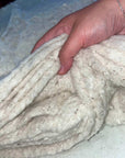 Hand holding 100% cotton batting fabric, eco-friendly and hypoallergenic.