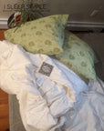 Washable wool duvet displayed on bed with green printed pillows.