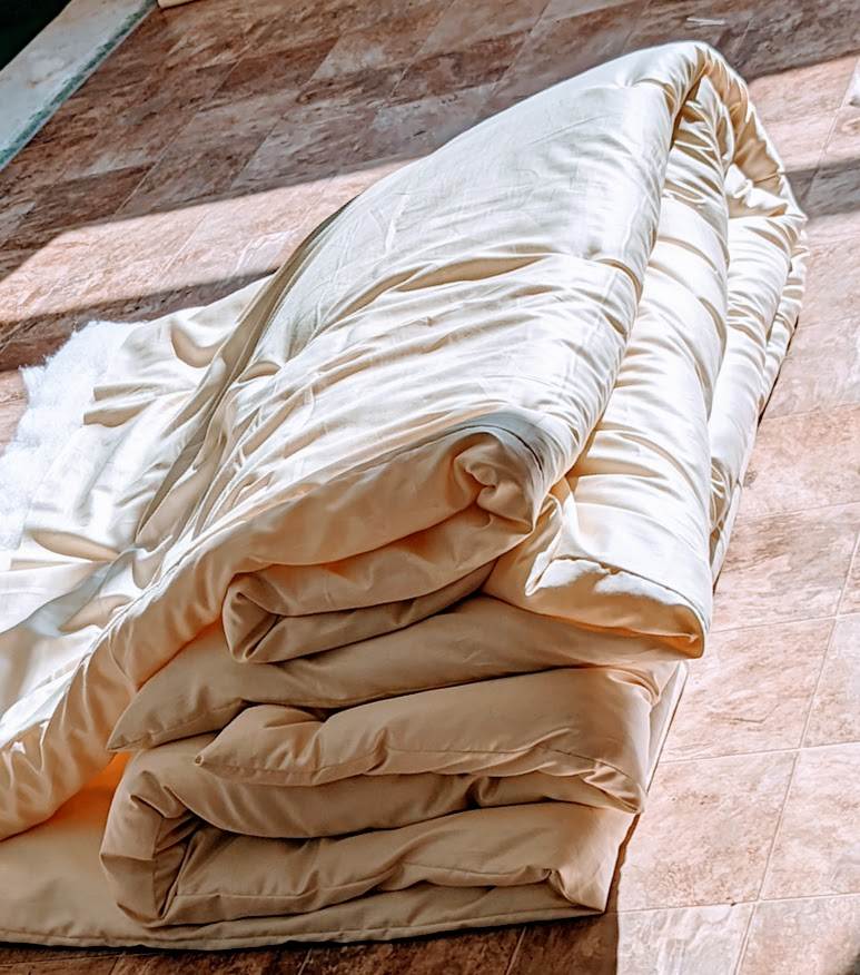 Handmade wool duvet made from sustainable New Zealand wool, folded on a wooden floor.