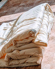 Handmade wool duvet made from sustainable New Zealand wool, folded on a wooden floor.