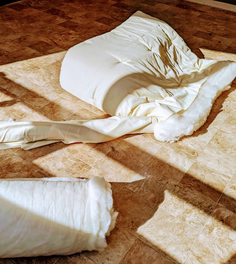 Handmade wool duvet on wooden floor, showcasing natural fibers and eco-conscious craft.