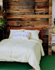 Handmade wool duvet on a bed with rustic decor and additional duvets stacked on shelves.