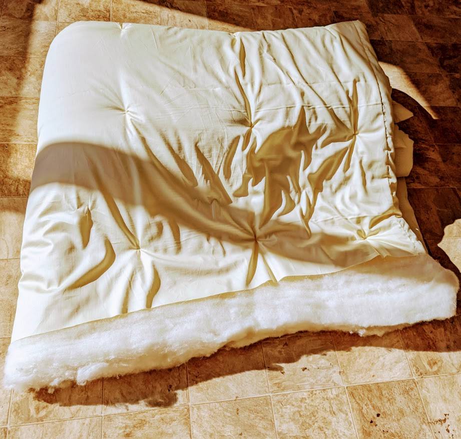 Handmade wool duvet on tiled floor, showcasing premium eco-friendly bedding.