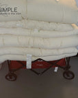 Cotton mattress topper stack on cart, handmade in USA for natural comfort.