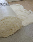 Organic wool batting roll on a textured surface, certified GOTS, highlighting eco-friendly and sustainable practices.