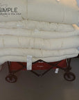 Organic cotton mattress toppers stacked on a red cart, promoting natural and breathable comfort.