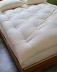 Organic wool mattress topper on bed for breathable, hypoallergenic comfort.