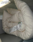 Organic cotton mattress topper, rolled up, showcasing plush texture and natural materials.