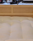 GOTS certified organic cotton and wool futon mattress on wooden bed frame in a cozy room setting.
