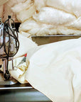 Sewing machine with fabric and stuffing for organic pillow covers in a workshop setting.