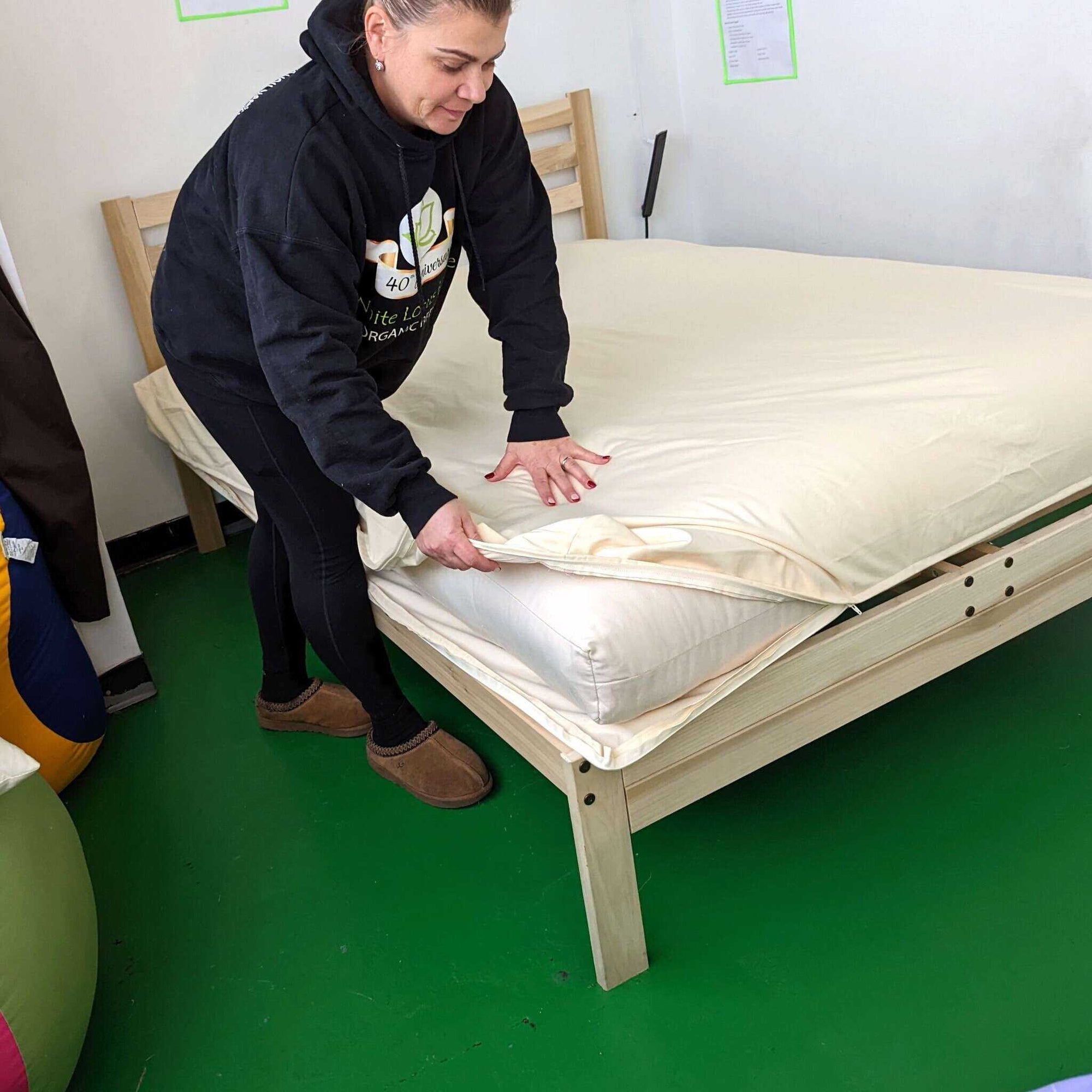 Zippered organic waterproof mattress protector being placed on bed frame