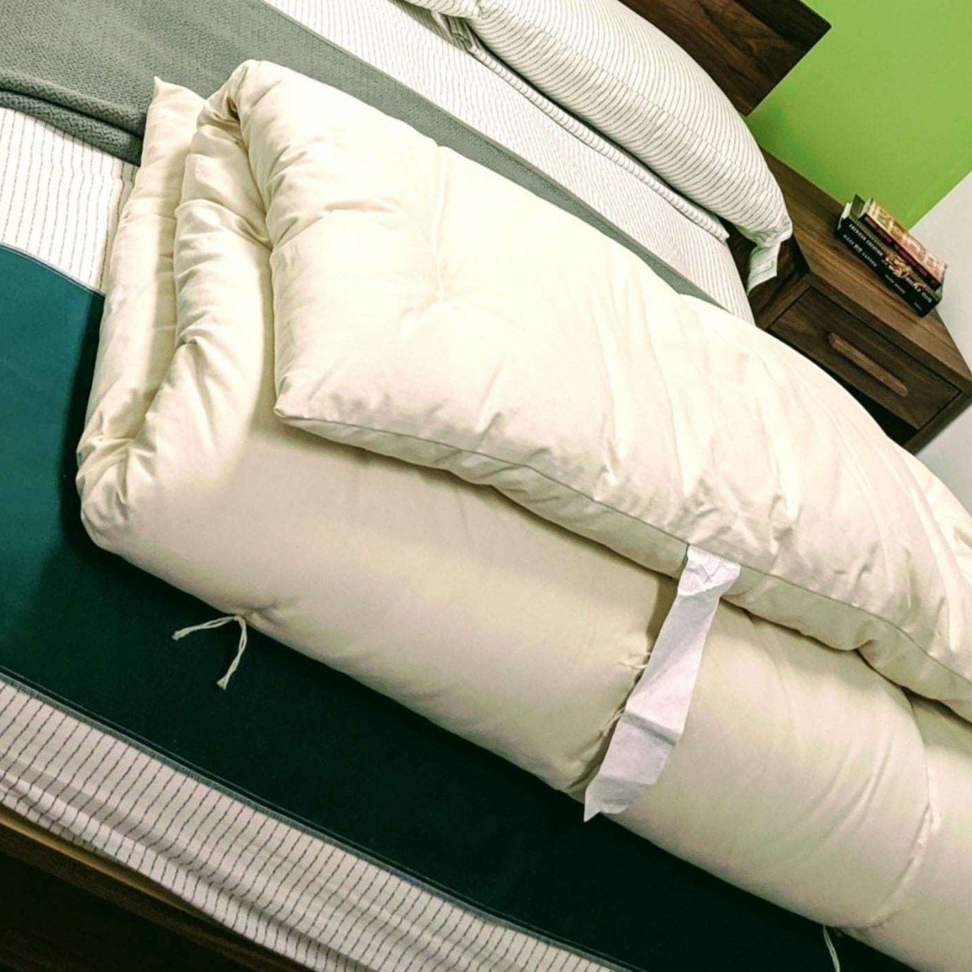 Cotton mattress topper on bed, showcasing its plushness and organic cotton material.