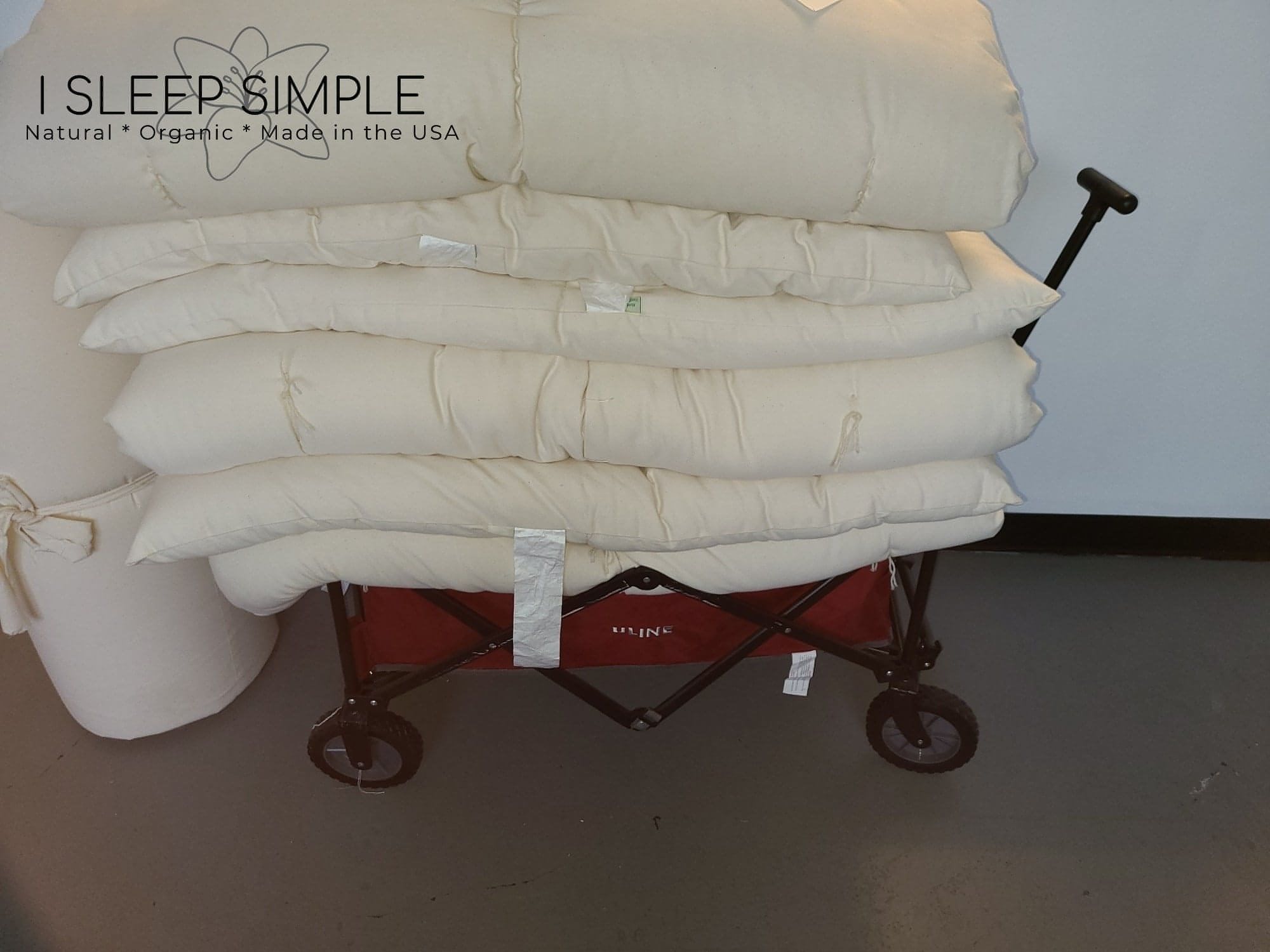 Cotton mattress topper stack on cart, handmade in USA for natural comfort.