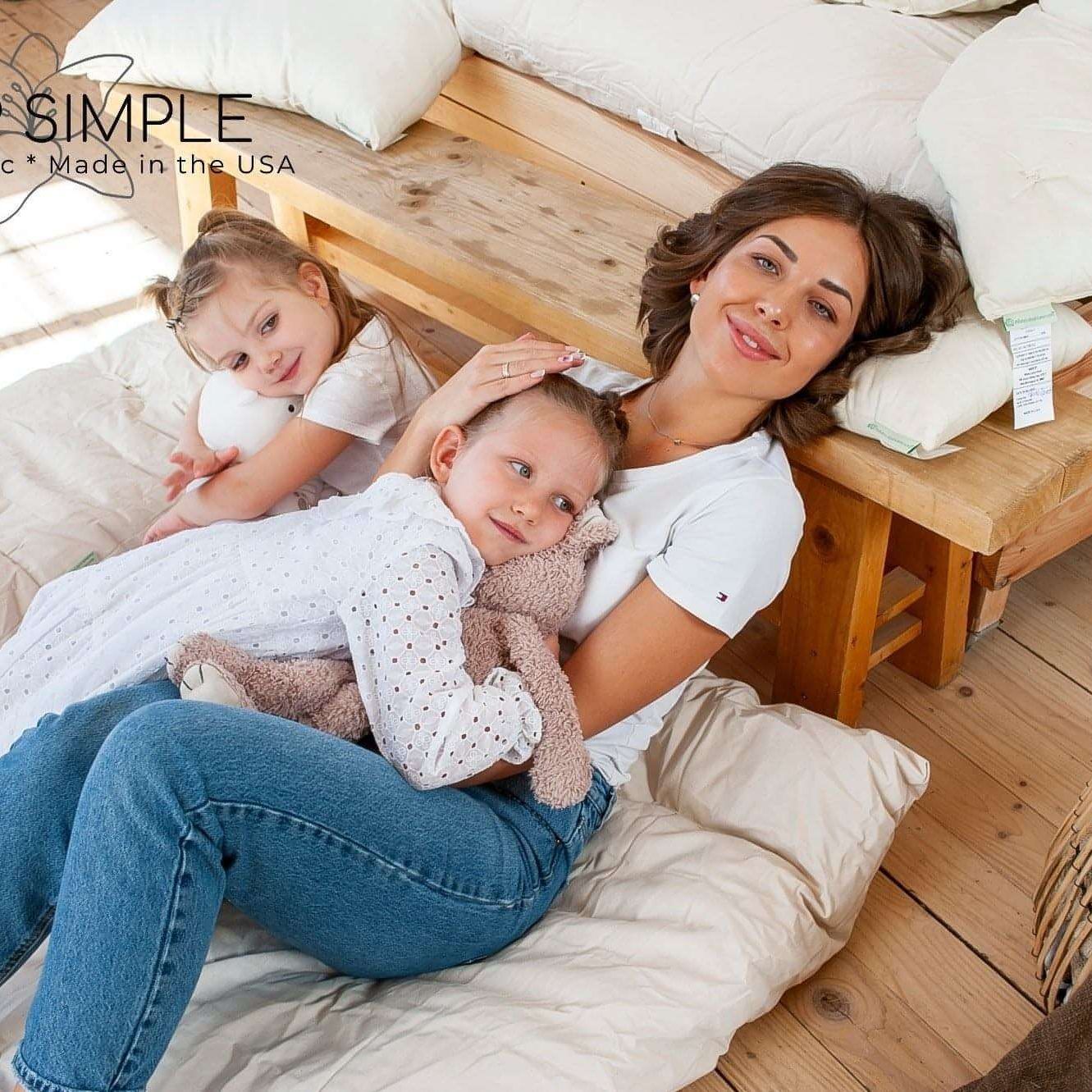 Family relaxing on a bed with a cotton mattress topper, showcasing natural comfort and luxury.
