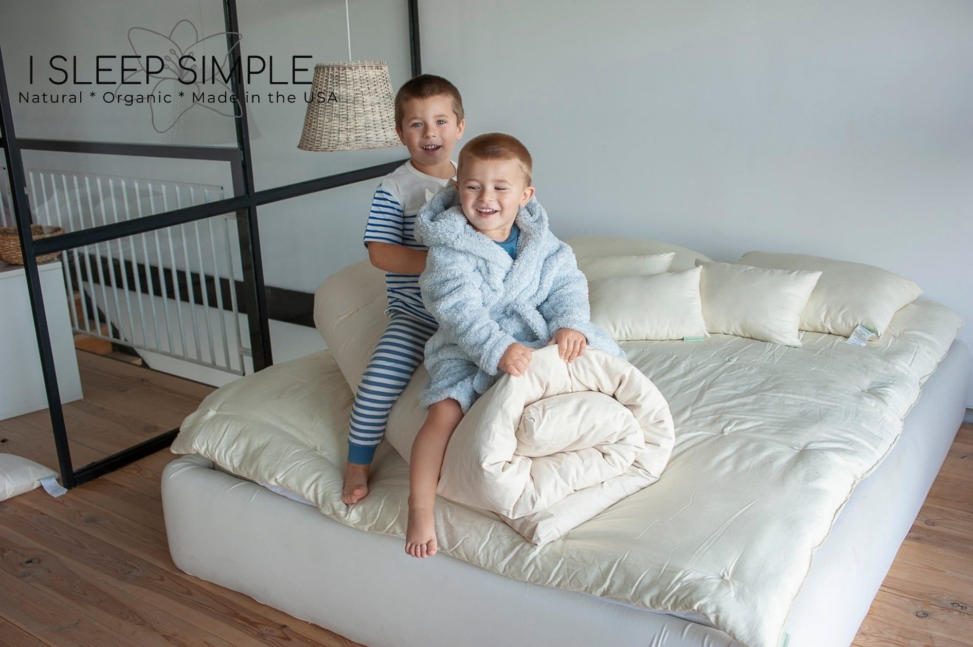 Children sitting on a bed with a cotton mattress topper.