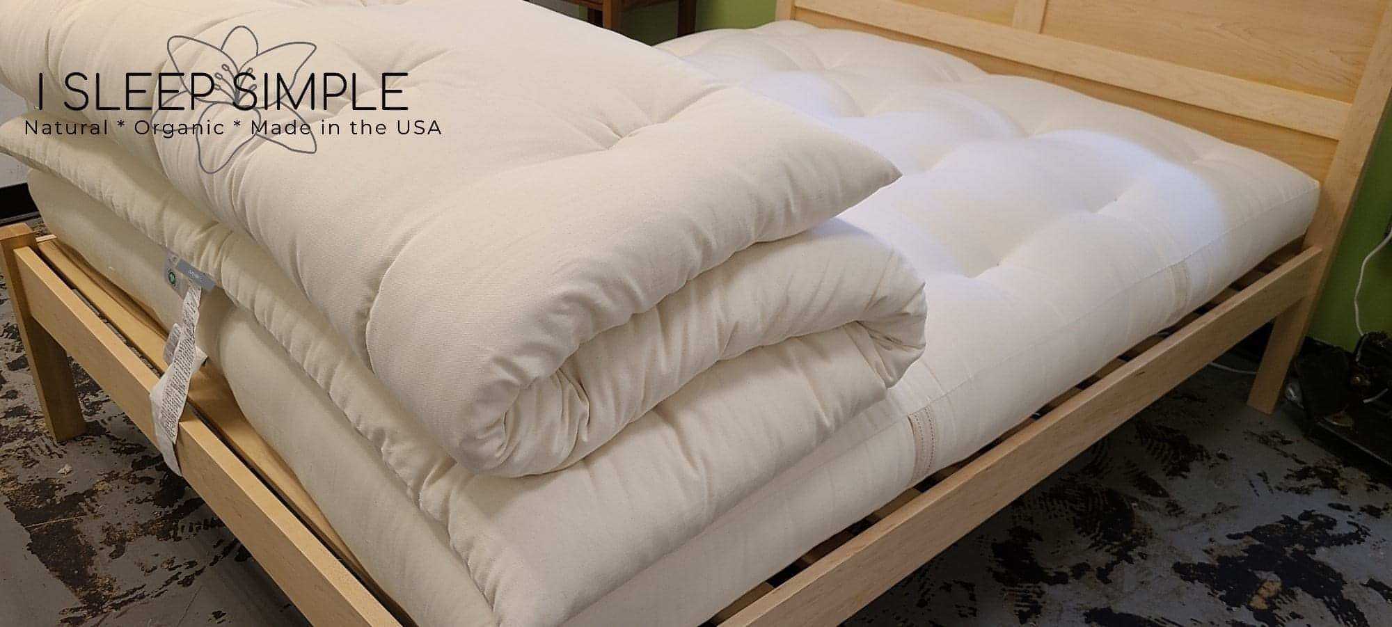 GOTS Certified Organic Topper made of cotton on a wooden bed frame.