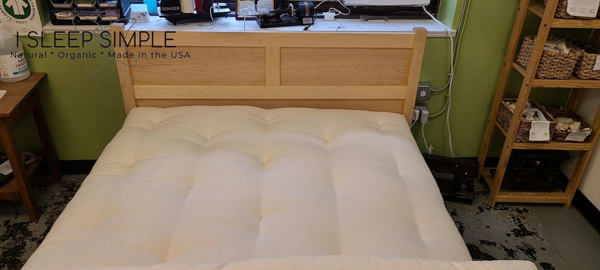 GOTS certified organic cotton and wool futon mattress on wooden bed frame in a cozy room setting.