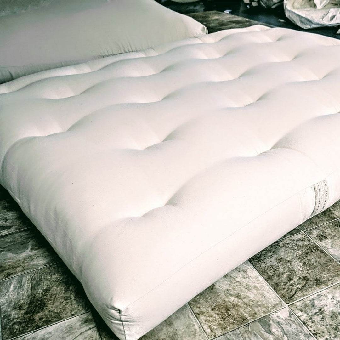 GOTS Certified Organic Cotton and Wool Futon Mattress on floor showing natural fabric and tufting details.